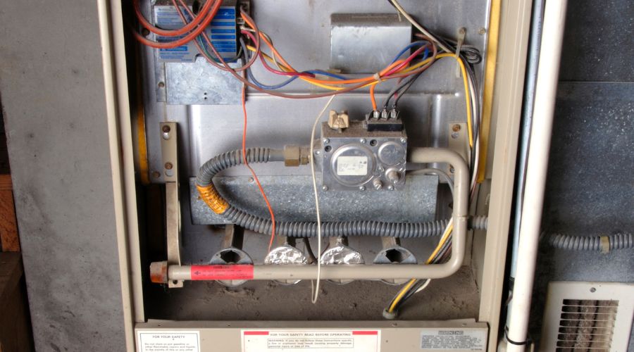 Heating system components showing wiring, gas valve, and safety features, relevant to identifying heating hazards and maintenance needs for homeowners.